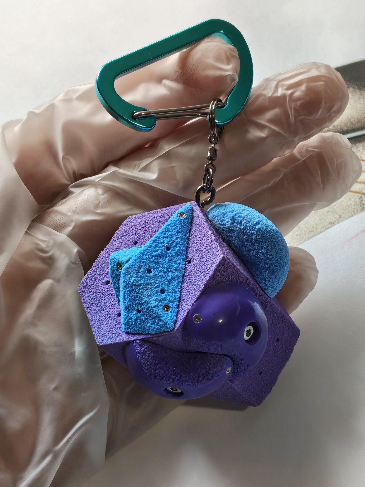 Purple and blue miniature climbing volume keychain held in one hand